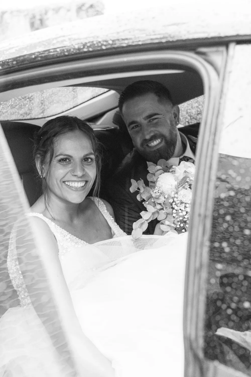 Novia y novio sonriendo dentro de un coche el día de su boda
