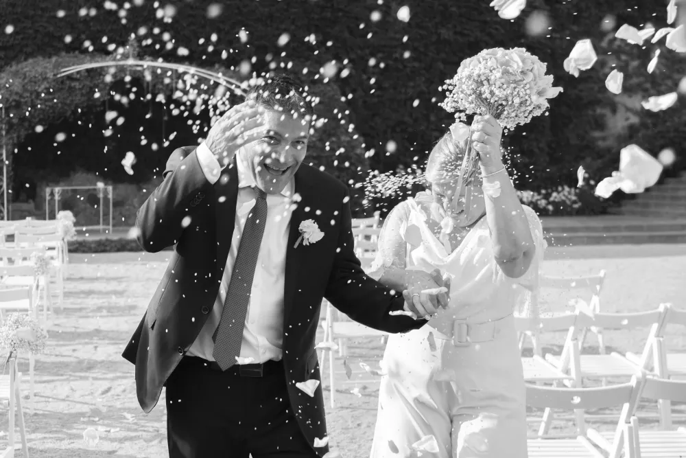 Novios caminando entre una lluvia de arroz y pétalos tras la ceremonia