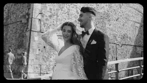Novios abrazados frente a un muro de piedra, fragmento de un vídeo de boda