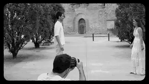 Novios corriendo el uno hacia el otro en un jardín mientras un videógrafo los graba